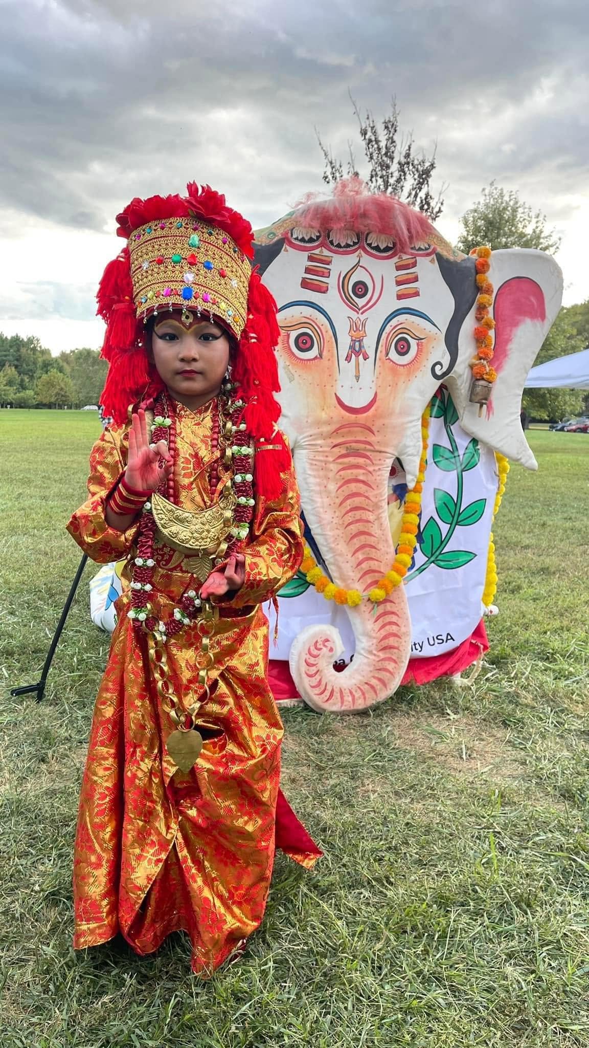 Child in traditional costume beside a Ganesh chariot effigy