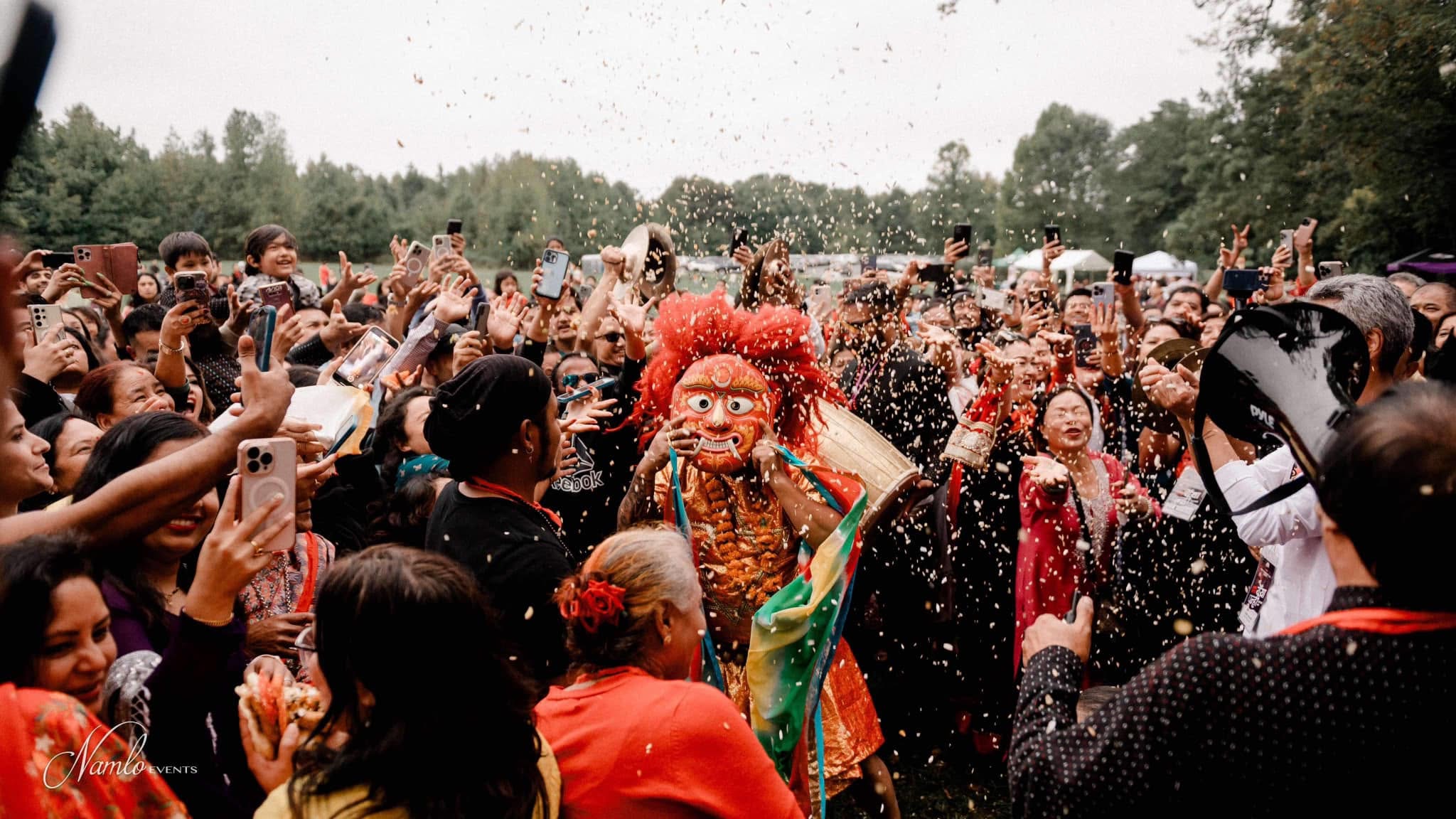 Crowd celebrating with rice toss around a traditional Lakhe dancer at a past Yenya Punhi celebration